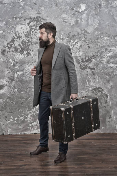 trendy man with travel suitcase. Vintage trip bagage. Modern life. Male fashion model. Mature businessman with beard. Travelling fot business. Casual style. Brutal bearded hipster in denim wear - Fotografie, Obrázek