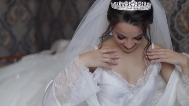 Braut in weißem Boudoir-Kleid, Schleier und in einer Seidenrobe. Hochzeitsvorbereitungen vor der Trauung - Filmmaterial, Video