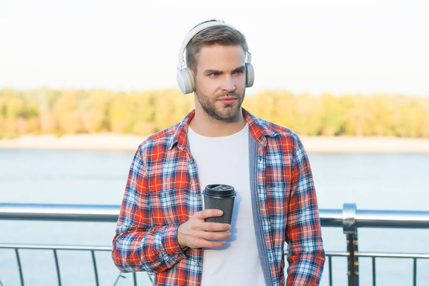 What a great morning. time to relax. new digital technology. morning starts with fresh coffee. handsome young man in headphones. modern life. listen to music. guy casual style drink take away coffee - Foto, afbeelding
