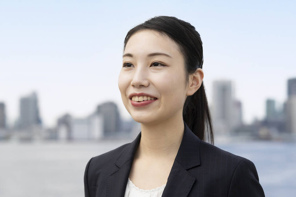 笑顔で屋外に立つアジアの若いビジネス女性 - 写真・画像