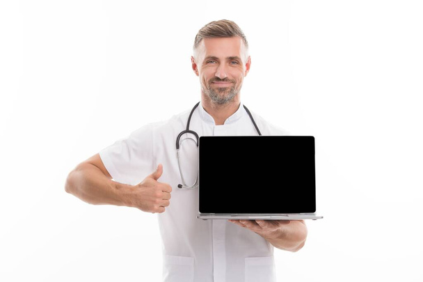man therapist with laptop. medical worker with stethoscope show thumb up. technology in modern medicine. make an appointment with doctor online. physician consultation on covid. Your personal account - Foto, afbeelding