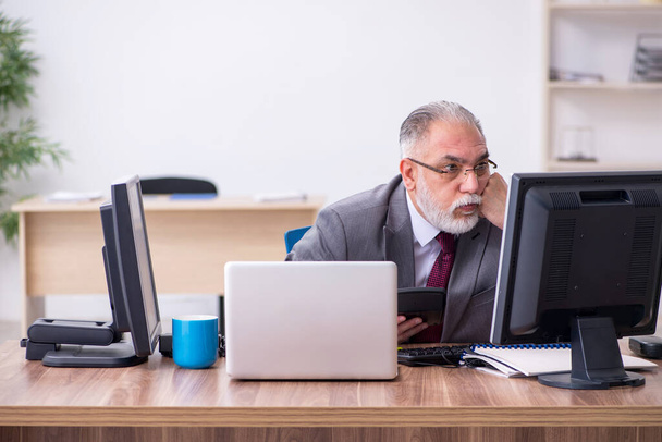 Old male boss sitting at desktop in the office - Foto, Bild