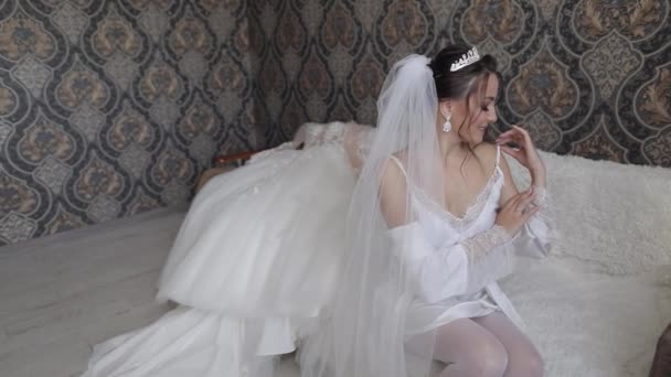 Νύφη με λευκό μπουντουάρ φόρεμα, πέπλο και μεταξωτή ρόμπα. Γάμος πρωινές προετοιμασίες πριν από την τελετή - Πλάνα, βίντεο