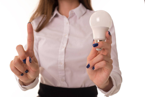 Girl in a shirt holds a light bulb in her hand. - 写真・画像