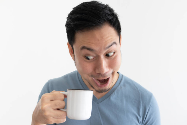 Funny wow face of man in blue t-shirt drinks coffee from white mug. - Zdjęcie, obraz