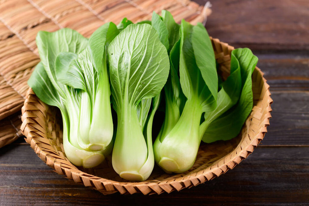 Fresh Bok Choy or Pak Choi (Chinese cabbage) in bamboo basket on wooden background, Organic vegetables - Фото, изображение