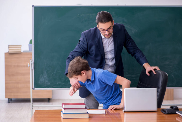Young male teacher and schoolboy in the classroom - Zdjęcie, obraz