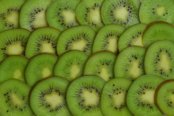 Close-up de fatias de kiwi em fatias encontram-se em fileiras ao longo da foto - Foto, Imagem