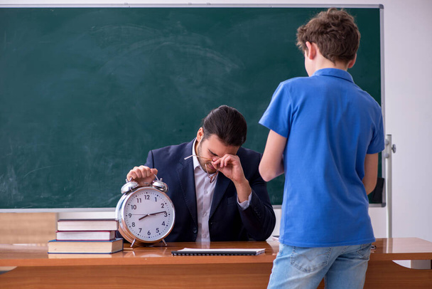 Young male teacher and schoolboy in the classroom - Photo, image
