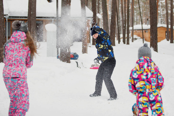 Mama tata i córka bawią się w śnieżki w pobliżu domu w zimowym lesie. Skupienie selektywne. - Zdjęcie, obraz