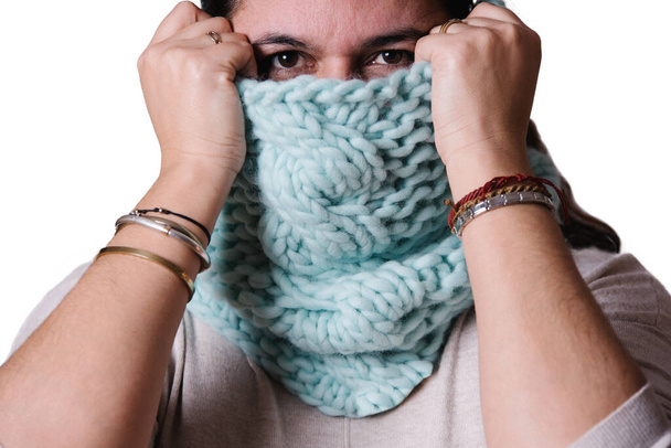 Portrait of a woman covering part of her face with a hand knitted scarf on white background. Winter concept - Photo, Image
