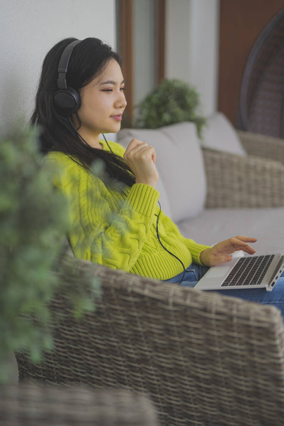 Fiatal ázsiai nő hallgatja a zenét a laptop segítségével fejhallgató - Fotó, kép