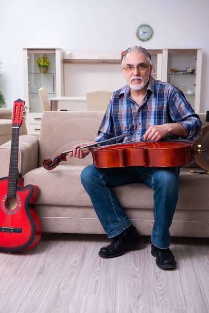 Riparatore anziano di sesso maschile che ripara strumenti musicali a casa - Foto, immagini