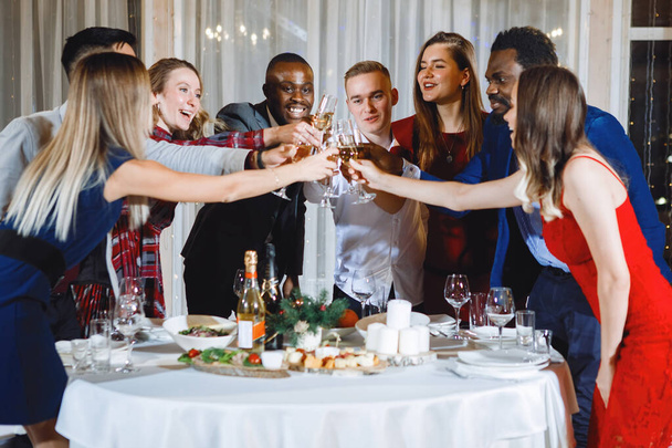 Jovens multinacionais se divertem engasgando copos com champanhe no festival. Foco seletivo, luzes embaçadas. - Foto, Imagem