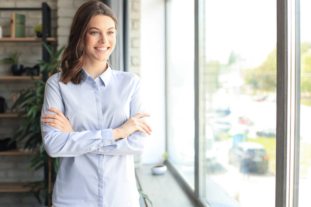Attractive business woman smiling while standing in the office - Valokuva, kuva