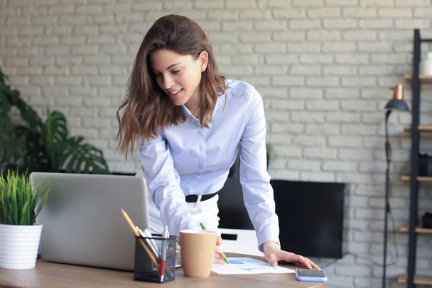 Young business woman standing in her home office reading notes - Photo, image