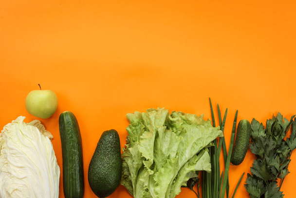 Green vegetables and fruits on the orange background. Copy space.  - Φωτογραφία, εικόνα