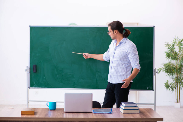 Young male teacher in front of blackboard - Foto, imagen