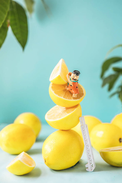 Funny lemons with toy man Flintstones  on a blue background. Abstract concept, food for kids - Foto, afbeelding