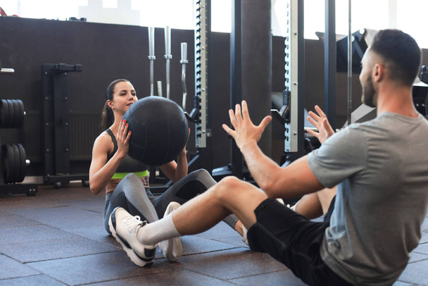 Beautiful young sports couple is working out with medicine ball in gym - Foto, Imagem