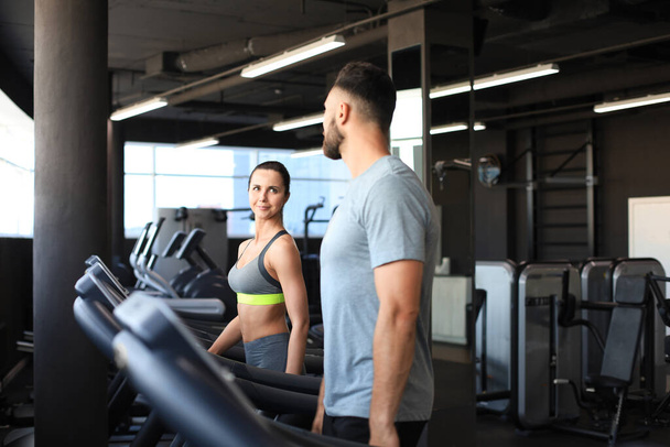 Healthy sport couple running on a treadmill in a sport gym - Фото, зображення