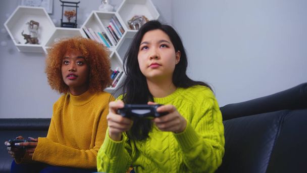 Twee jonge vrouwen die joystick controller gebruiken om videogame te spelen. Wedstrijd wint en verliest - Foto, afbeelding