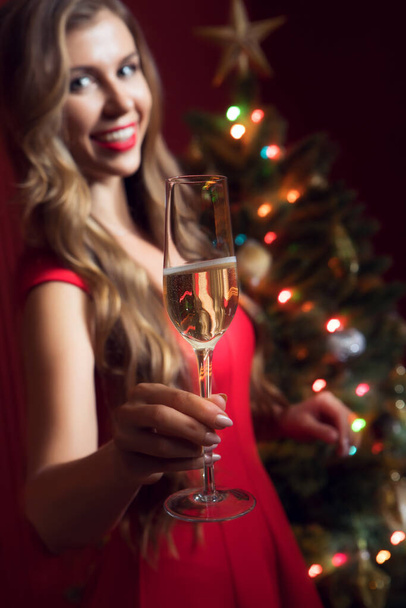 portrait of nice woman in red dress with champagne  in christmas environment - Fotó, kép