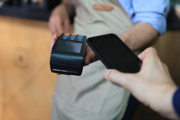 Cliente que utiliza el teléfono inteligente para el pago al propietario en el restaurante cafetería, tecnología sin efectivo - Foto, Imagen