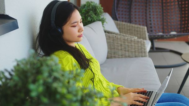 Jeune femme asiatique, pigiste, travaillant sur son ordinateur portable avec casque. Enseignement à distance ou concept de travail à distance - Photo, image