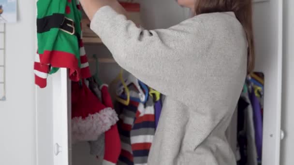 Äiti kotiäiti purkaa joulupuvut pienen tyttären kaapissa, - Materiaali, video