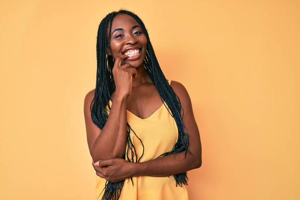 African american woman with braids wearing casual clothes looking confident at the camera with smile with crossed arms and hand raised on chin. thinking positive.  - Photo, Image