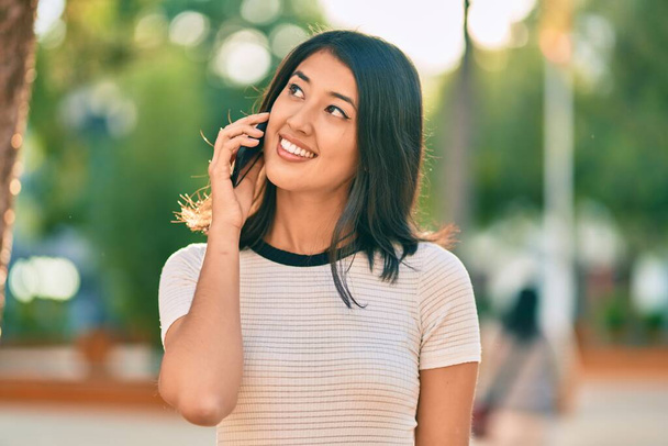 Joven mujer hispana sonriendo feliz hablando en el smartphone de la ciudad. - Foto, imagen
