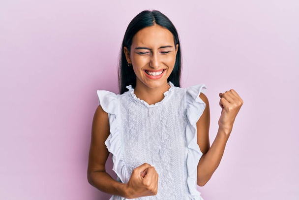 Young brunette woman wearing elegant summer shirt celebrating surprised and amazed for success with arms raised and eyes closed  - Photo, Image