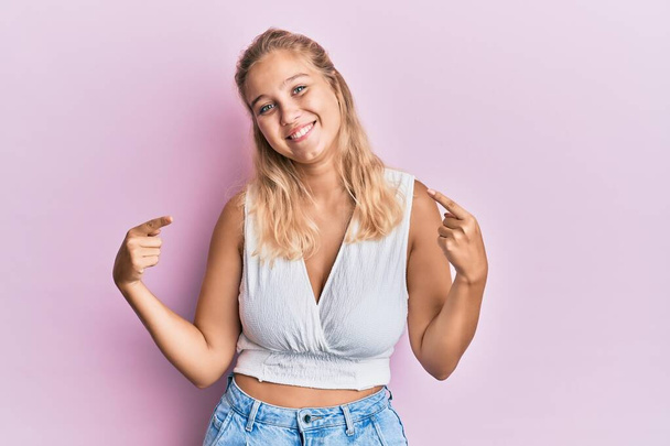 jong blond meisje dragen casual kleding kijken zelfverzekerd met glimlach op gezicht wijzend zichzelf met vingers trots en gelukkig.  - Foto, afbeelding