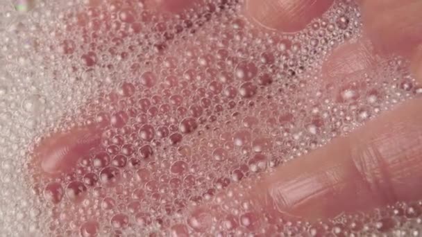 Много пузырей пены закрываются под рукой в воде макросъемки. Селективный фокус - Кадры, видео