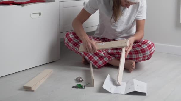 Een vrouw in Kerst thuis kleding verzamelt een kleine houten plank in de kinderkamer - Video