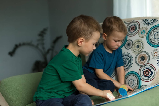 Дети дома смотрят на книгу на диване. - Фото, изображение