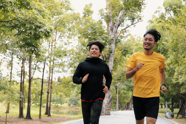 Két fiatal ázsiai egészséges férfi fut együtt a parkban, testmozgás és sport gyakornoki koncepció   - Fotó, kép