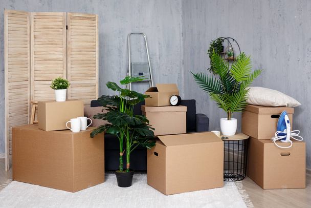 concepto de día móvil - cajas de cartón marrón con pertenencias apiladas en casa nueva - Foto, imagen