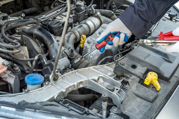 mechanic's hand with screwdriver repair or check car  in garage. automotive service - Zdjęcie, obraz