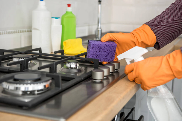  Person mit Handschuh und Putzset waschen Küchenmöbel. Schützen Sie sich. Hausarbeit - Foto, Bild