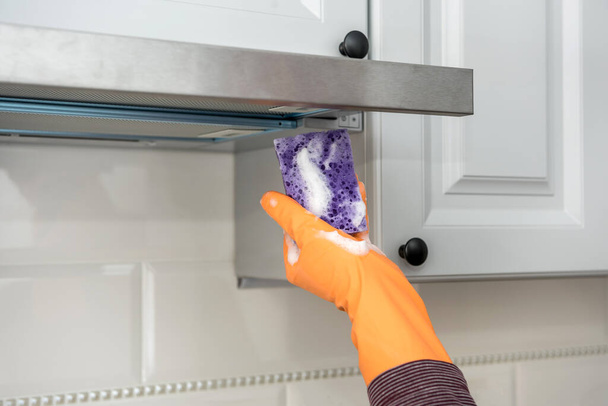 male hands in protective gloves cleaning the kitchen hood with rag and spray bottle . housekeeper - Photo, Image