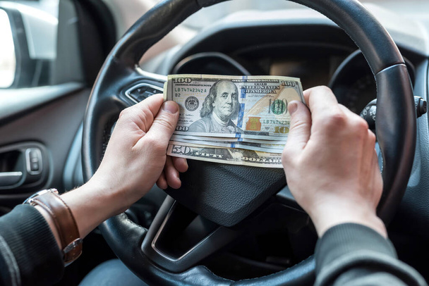Billetes de 100 dólares en mano masculina, hombre dentro en el coche. Concepto de sobornos, seguros o alquileres, comprar - Foto, imagen