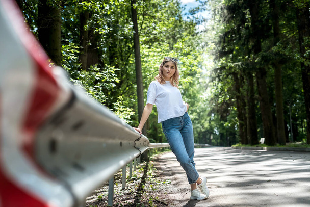 joven dama en jeans y una camiseta blanca tiene un gran tiempo en la naturaleza en el bosque. verano - Foto, Imagen