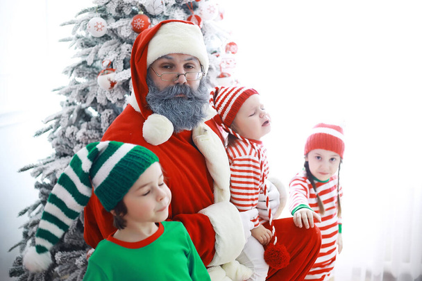 Pomocnicy.Cute dzieci w kostiumach elfa Bożego Narodzenia w pokoju pięknie urządzone na Boże Narodzenie. Czas cudów. Prezenty od Świętego Mikołaja - Zdjęcie, obraz