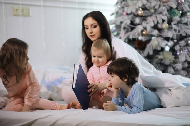 A family with children having fun on the bed under the covers during Christmas holidays. - Photo, Image