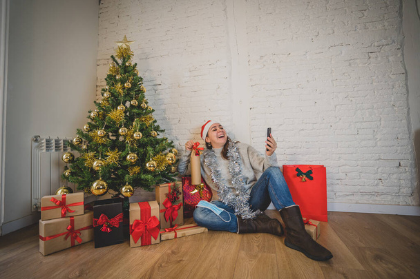 Happy woman in quarantine celebrating virtual christmas video calling family and friend on smart mobile cell phone. Virtual holiday gathering online due to coronavirus quarantine social distancing. - Foto, Bild
