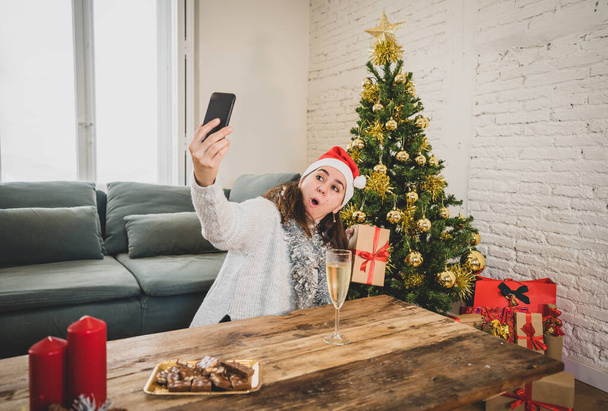 Happy woman in quarantine celebrating virtual christmas video calling family and friend on smart mobile cell phone. Virtual holiday gathering online due to coronavirus quarantine social distancing. - Foto, Bild