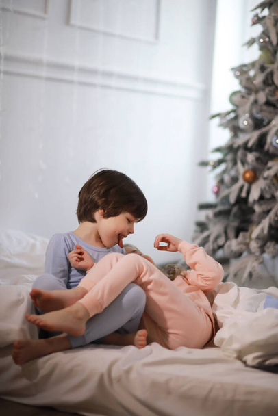 Сім'я з дітьми розважається на ліжку під обкладинками під час різдвяних канікул
. - Фото, зображення
