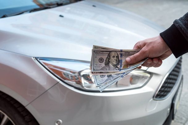 comprar nuevo concepto de acr. hombre sosteniendo dólar por auto de alquiler. financiación - Foto, imagen